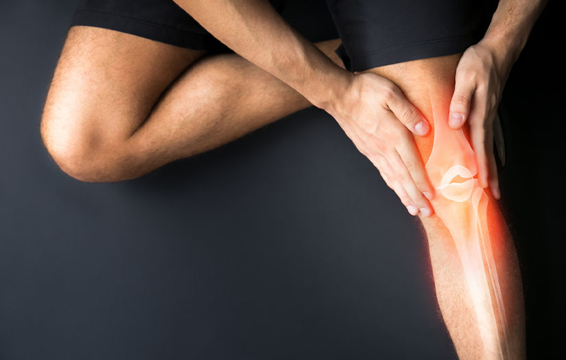 male sitting on ground holding knee with anatomy of knee