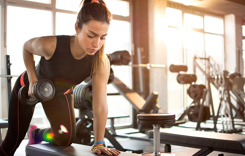 female doing kneeling row on bench